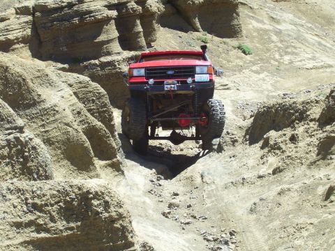 1989 Ford Bronco - A red 1989 Ford Bronco navigates a challenging rocky terrain, its off-road capabilities.
