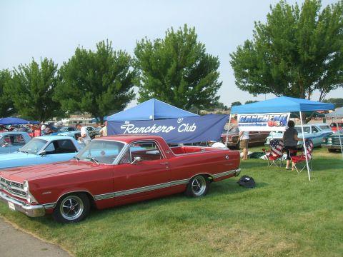 1974 Ford Ranchero - A red Ford Ranchero is displayed at a car show, with other vehicles and tents visible.