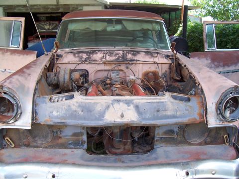 1955 Ford Customline - This 1955 Ford Customline shows significant rust and wear, with its hood open revealing the engine bay.