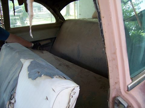 1955 Ford Customline - Interior view of a 1955 Ford Customline, showing worn seats and dust accumulation.