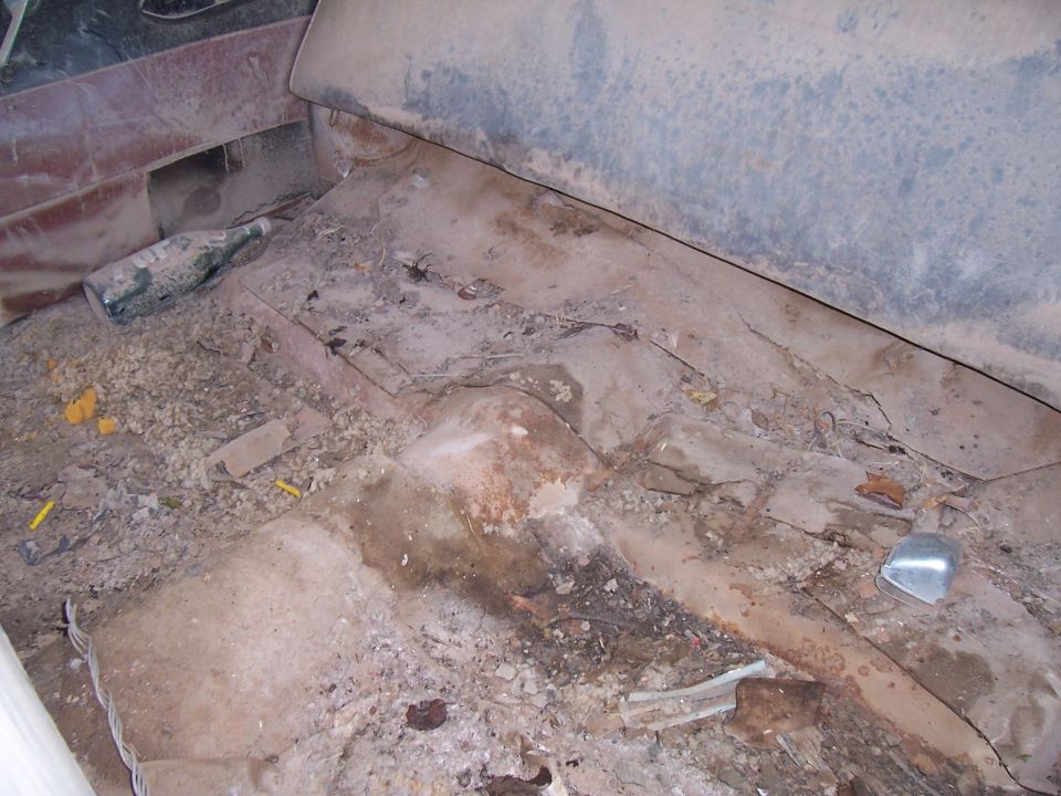 Dirty car interior floor with a bottle and debris