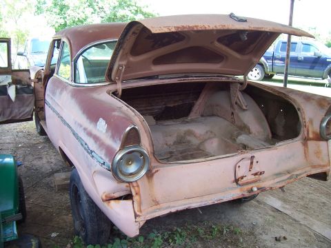 1955 Ford Customline - Rear view of a weathered 1955 Ford Customline, trunk lid ajar, revealing its interior.