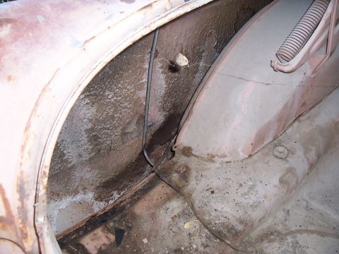 1955 Ford Customline - Interior view of a 1955 Ford Customline's wheel well, revealing signs of wear and tear.