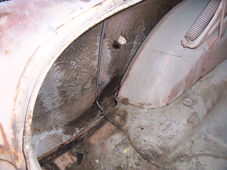 1955 Ford Customline wheel well interior, showing rust and dirt