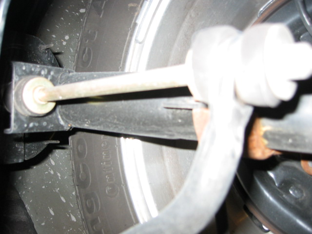 Close-up of a white-painted sway bar end link and suspension arm inside a wheel well