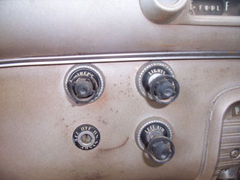 1955 Ford Customline - Close-up of vintage car dashboard controls, including switches for wipers, lights, and air, along with a start ignition.