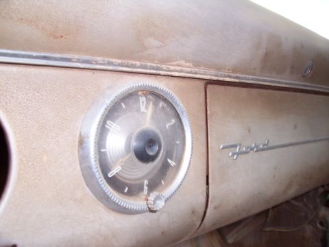 1955 Ford Customline - The dashboard of a 1955 Ford Customline features a prominent clock and the Ford emblem.