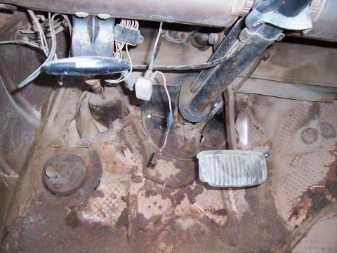1955 Ford Customline - Interior view of the floor pan and pedals in a 1955 Ford Customline, showing signs of rust.