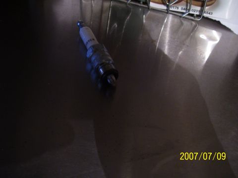 1990 Jeep Cherokee - A single spark plug is shown on a reflective surface, with a date stamp and website visible.