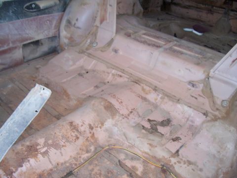 1955 Ford Customline - The interior floor of a vehicle shows significant rust and wear, indicating it is undergoing restoration.