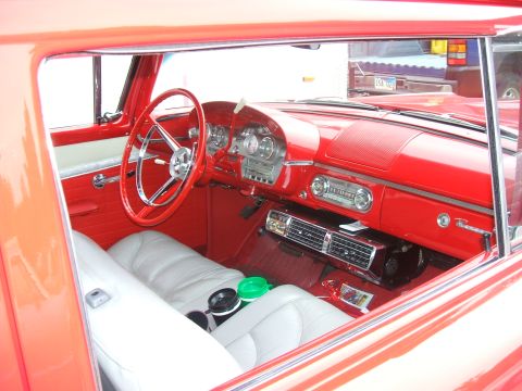 1974 Ford Ranchero - The interior of a classic car features a red dashboard and white upholstery, with a vintage radio visible.