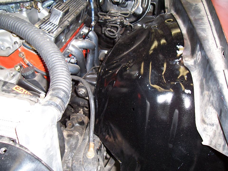 Engine bay with radiator hose, exhaust manifold, and black inner fender well
