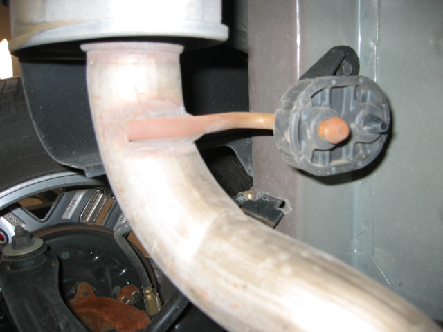 Exhaust downpipe and rubber hanger near front brake rotor under a vehicle