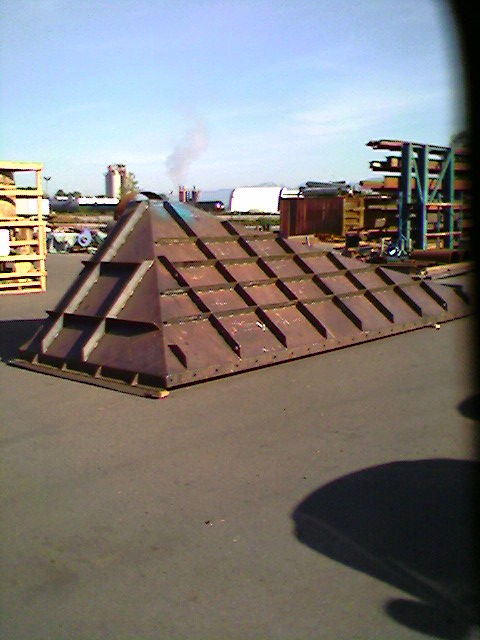 1989 Ford Bronco - A large, rusted metal pyramid structure sits on pavement in an industrial area.