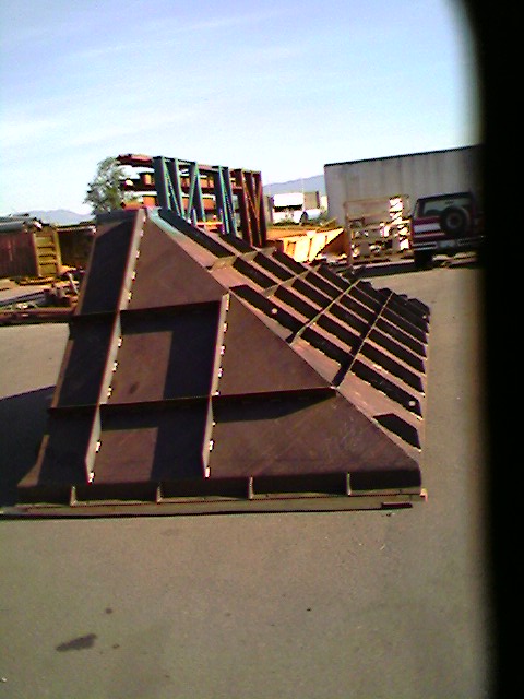 1989 Ford Bronco - A metal ramp structure sits in an outdoor lot with a truck visible in the distance.
