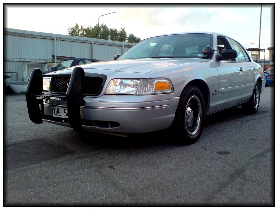 Silver 1998 Ford Crown Victoria with a black bull bar, parked on asphalt