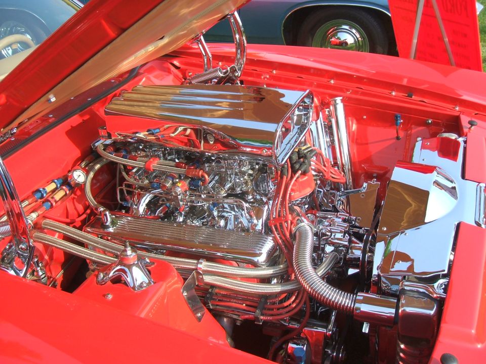 Engine bay with chrome intake and red spark plug wires. Supermotors.net logo visible