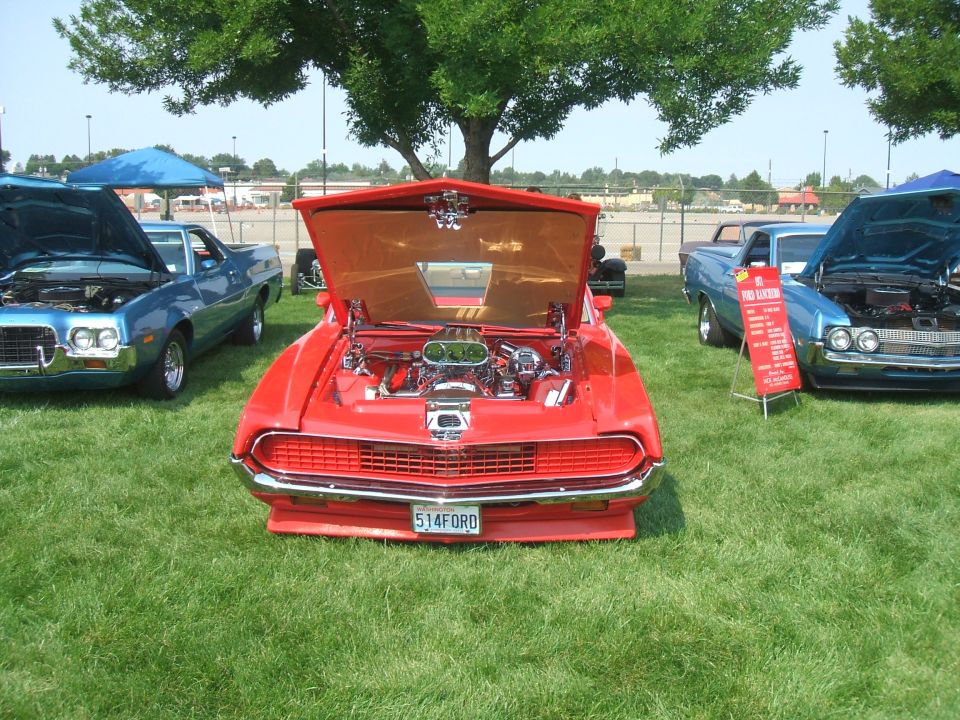 Red custom car with hood open, showing engine. Two blue cars parked nearby. License plate reads 514FORD