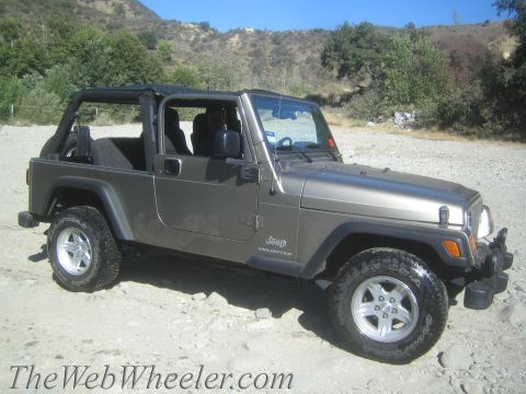 1987 Suzuki Samurai - This Jeep Wrangler Unlimited is seen parked on a dirt road with hills in the background.