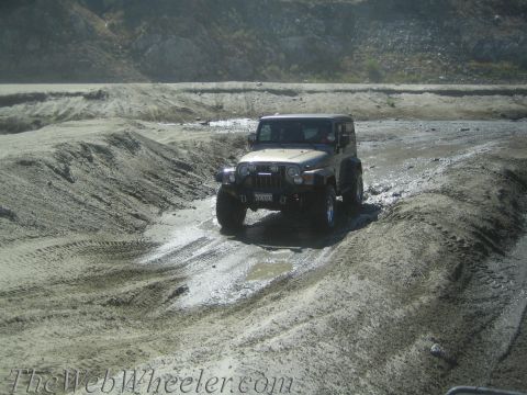 1987 Suzuki Samurai - A Jeep Wrangler navigates a challenging off-road terrain with mud and sand.