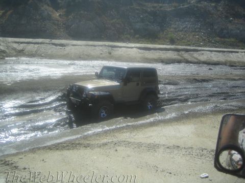 1987 Suzuki Samurai - Jeep Wrangler navigating through a muddy, off-road environment.