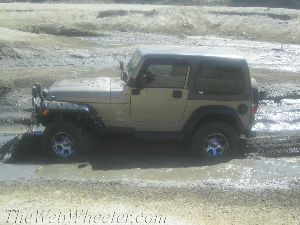 Tan Jeep Wrangler stuck in mud, side view