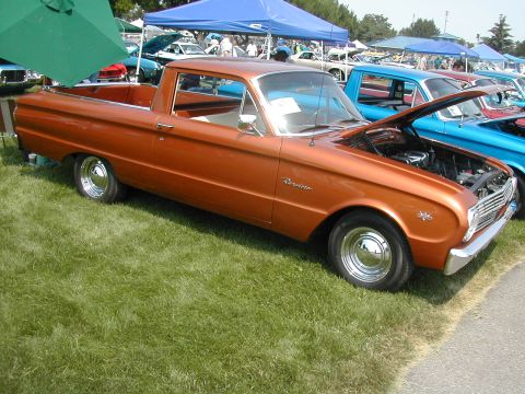 1972 Ford Ranchero - Orange pickup truck at a car show, hood open, with other vehicles visible.