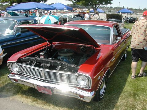 1972 Ford Ranchero - Red 1960s Ford Ranchero at a car show, hood open, next to a blue Ford Falcon.