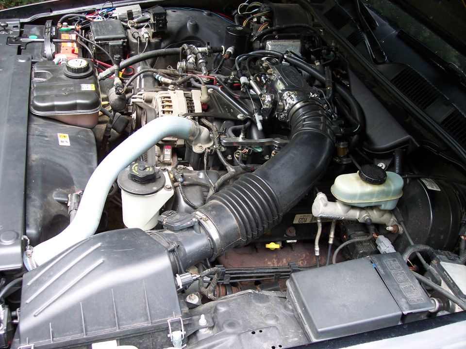 V8 engine bay showing airbox, intake tube, alternator, coil pack and master cylinder