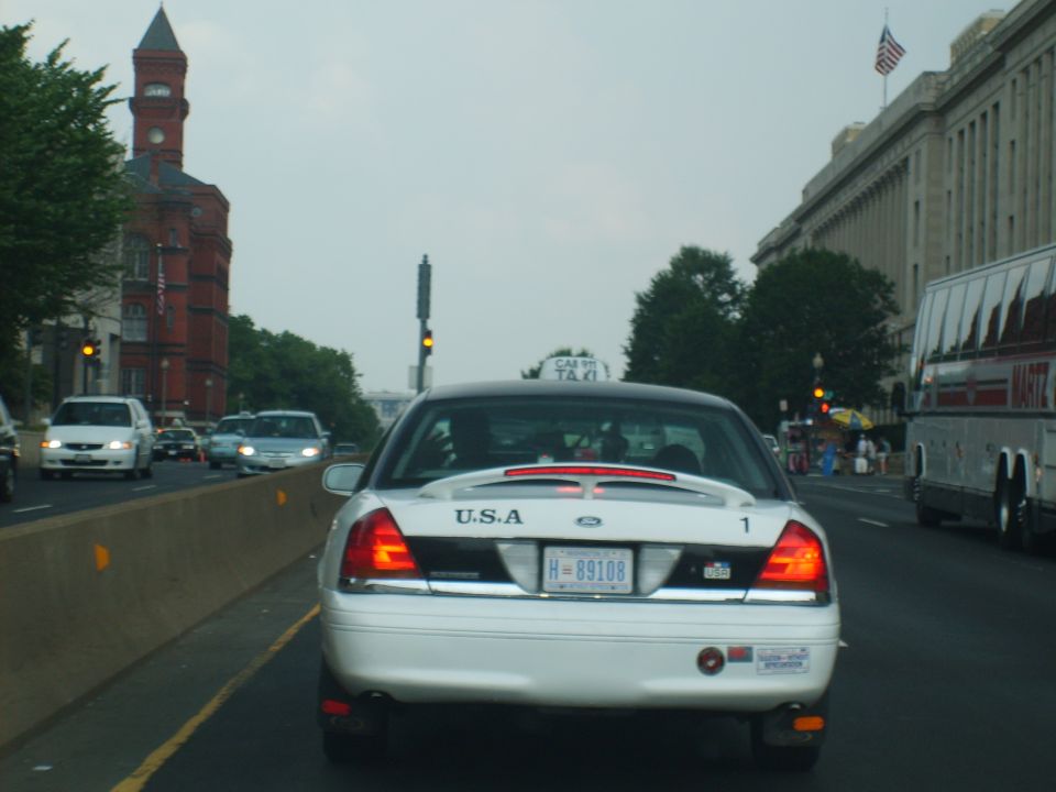 White 2004 Ford Crown Victoria taxi with a dented rear bumper and a license plate reading H-89108