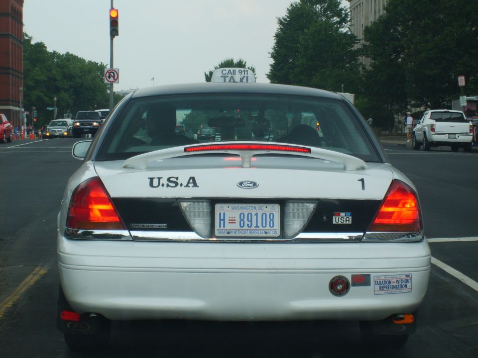 Rear view of a white taxi with a spoiler and license plate H=89108