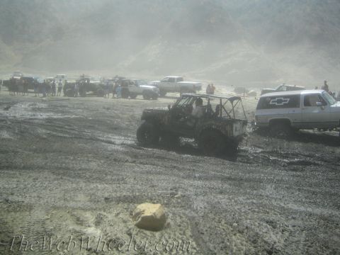 1987 Suzuki Samurai - Multiple off-road vehicles and people are gathered in a muddy, dusty environment.