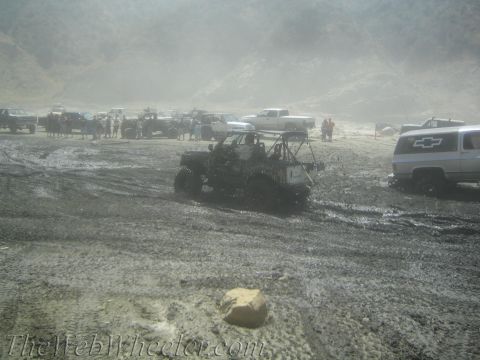 1987 Suzuki Samurai - Several off-road vehicles are stuck in the mud, with spectators watching in the background.