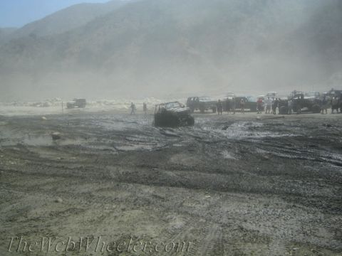 1987 Suzuki Samurai - A group of off-road vehicles navigate a muddy terrain, with some appearing to be stuck.
