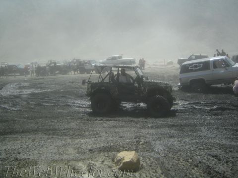 1987 Suzuki Samurai - Multiple off-road vehicles are stuck in a muddy terrain, with spectators observing the scene.
