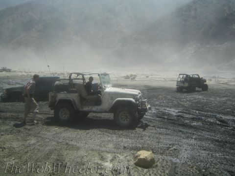 1987 Suzuki Samurai - Off-road vehicles navigate challenging muddy terrain under hazy skies.