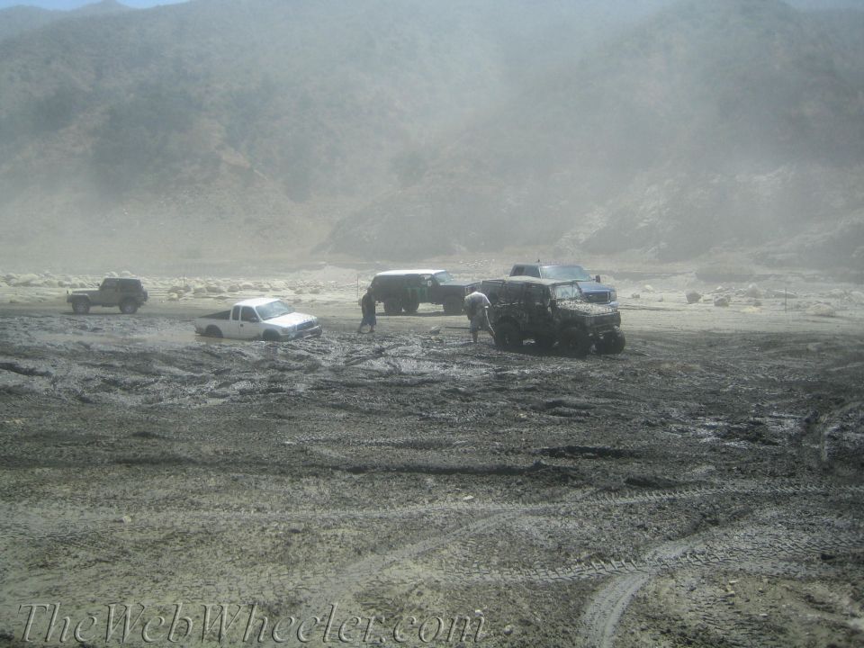 Several off-road vehicles stuck in a muddy, dusty landscape