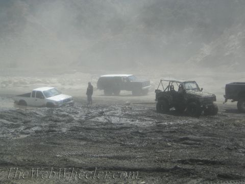 1987 Suzuki Samurai - Multiple off-road vehicles are stuck in a muddy area, with limited visibility due to dust or fog.