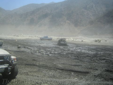 1987 Suzuki Samurai - Several off-road vehicles navigate a challenging muddy and dusty environment under a clear sky.