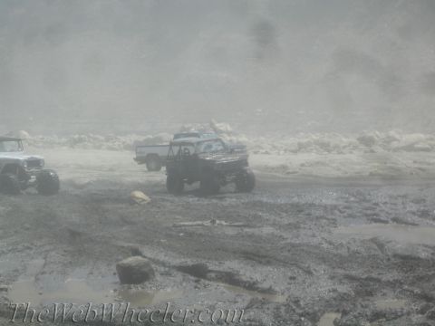 1987 Suzuki Samurai - Multiple modified trucks traverse a challenging, dusty, and muddy off-road course.