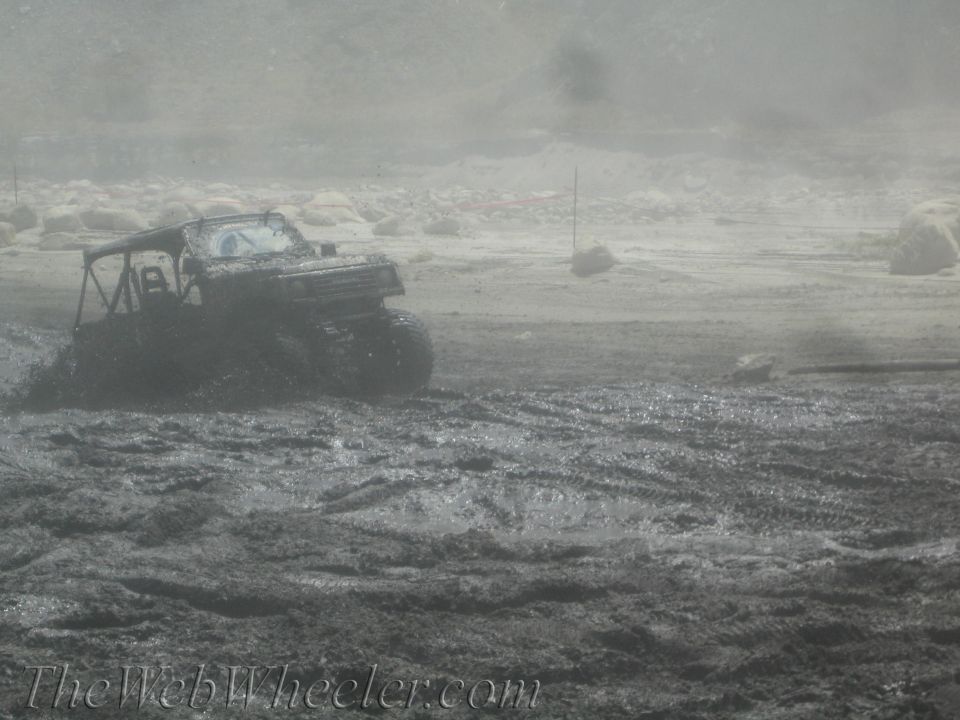 Mud-covered 1987 Suzuki Samurai driving through a muddy field