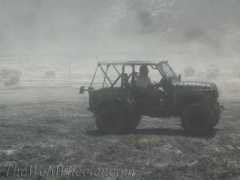 1987 Suzuki Samurai - An off-road vehicle navigates a challenging muddy terrain under hazy conditions.