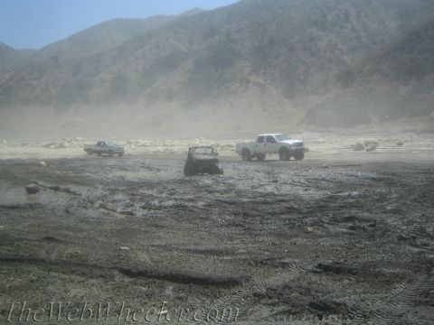 1987 Suzuki Samurai - Multiple trucks are visible in a desolate, dusty environment with hills in the distance.