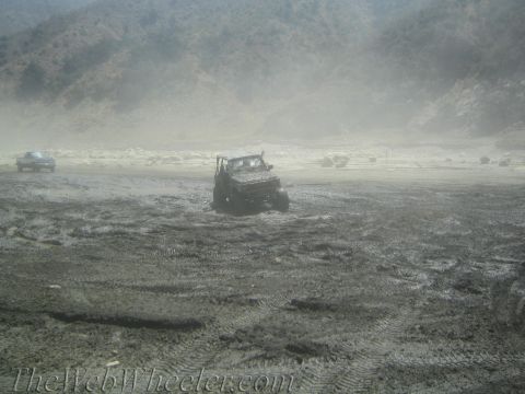 1987 Suzuki Samurai - A 1987 Suzuki Samurai is stuck in thick mud with another vehicle visible in the distance.