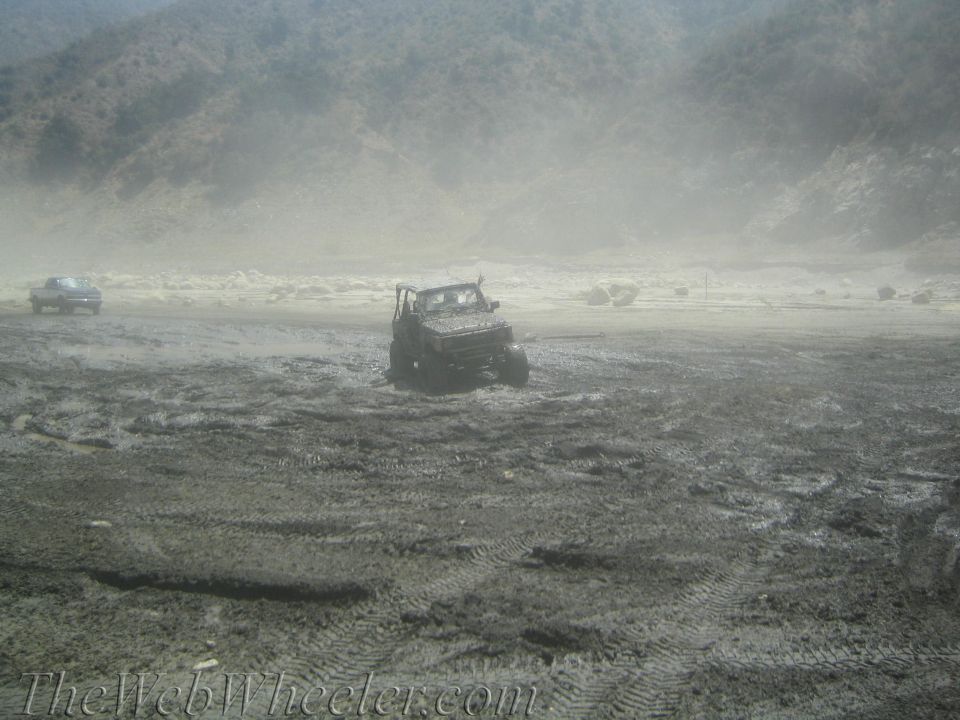 1987 Suzuki Samurai stuck in mud, front-right wheel deep, other vehicle in background