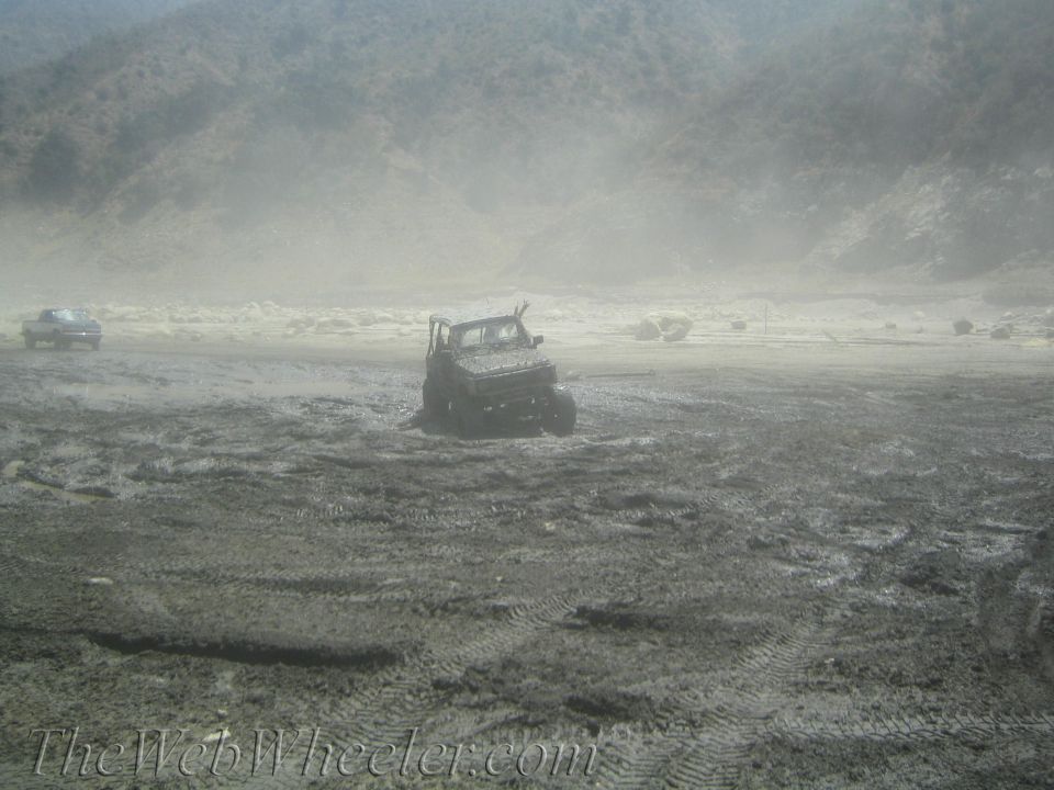 Off-road vehicle stuck in mud with another vehicle in the background
