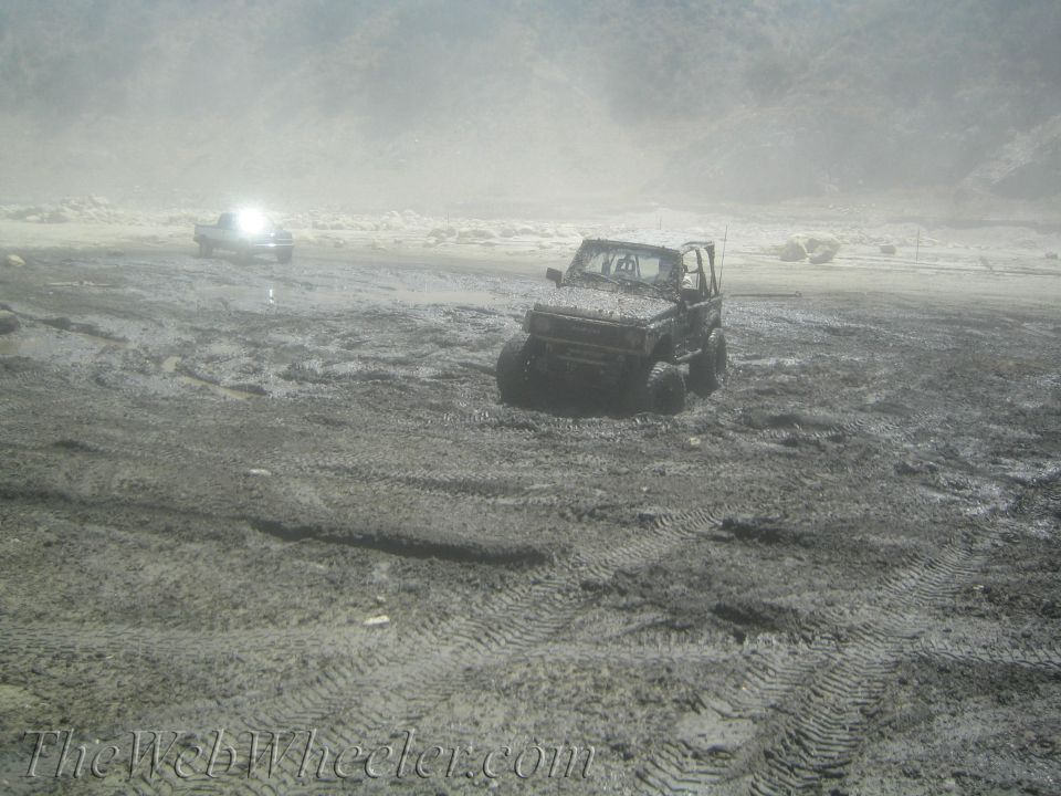Suzuki Samurai and a pickup truck stuck in mud, with tire tracks all over
