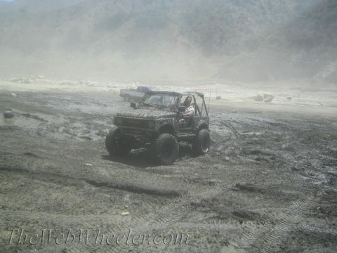 1987 Suzuki Samurai - This 1987 Suzuki Samurai navigates a muddy terrain, with another vehicle visible in the background.