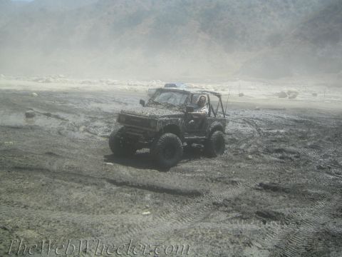 1987 Suzuki Samurai - Muddy Suzuki Samurai off-roading in a desolate, dusty landscape.
