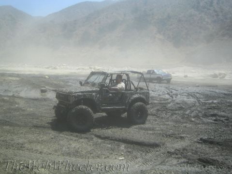 1987 Suzuki Samurai - A 1987 Suzuki Samurai navigates a dusty, muddy terrain with another vehicle in the background.